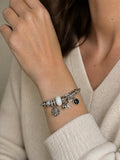 Bracelet manchette trésors argentés SYERA porté au poignet, charms perle et étoile